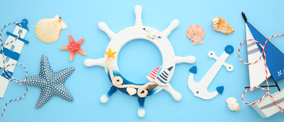 Nautical flat lay composition with maritime decor, wheel, starfish, seashells, anchor, lighthouse, boat on blue background