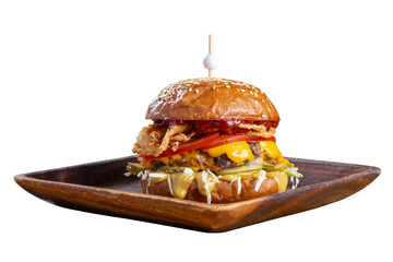 Big tasty burger with fried cutlet, cabbage salad, tomatoes and sauce on wooden plate isolated on white background.