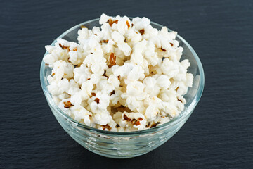Cooked popcorn grains in glass jare on black background.
