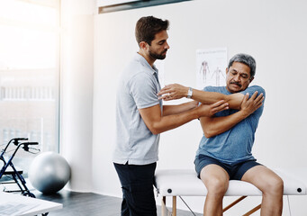 Physiotherapist, stretching and mature man in clinic, helping and healthcare with exercise and fitness. Hospital, workout and physiotherapy of patient, rehabilitation and concentration of person