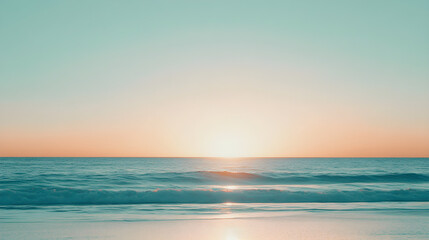 Obraz premium Bright orange sunset over a pale blue sky reflects beautifully on the tranquil beach waves creating a serene atmosphere