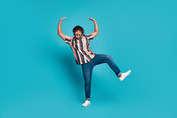 Full size photo of nice young man dance arms hold empty space wear shirt isolated on teal color background