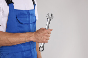 Auto mechanic with wrench on light grey background, closeup. Space for text