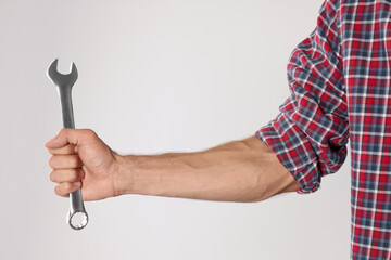 Auto mechanic with wrench on light grey background, closeup