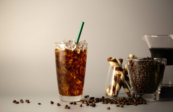 Iced americano coffee with coffee beans on grey background, Glass of black coffee, Beverage at coffee shop.