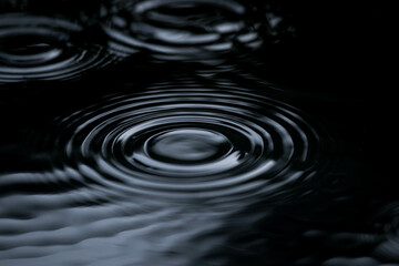 Ripple of water or water drop splash on black background. Abstract shape out of the water