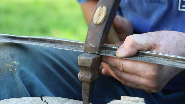 Sharpen the scythe. Sharpening the old scythe with a hammer. The farmer sharpens. rivets the scythe with a special hammer. MP4