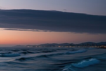 Obraz premium Twilight Glow on Ocean Waves with Clear Coastline and Serene Skyline