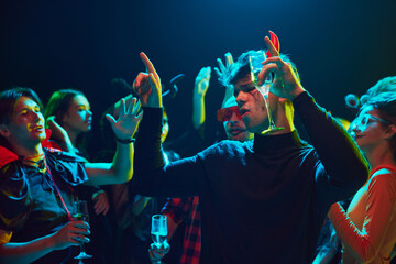 Friends at Halloween party at nightclub, posing with their spooky costumes, cheerfully dancing and enjoying spooky vibe. Concept of Halloween, holiday, party, leisure