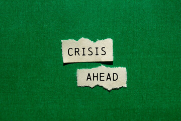 Crisis ahead message written on ripped torn paper pieces on green background. Conceptual crisis ahead symbol. Copy space.