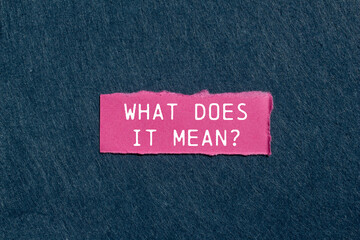 What does it mean question written on ripped pink torn paper piece on gray background. Conceptual...