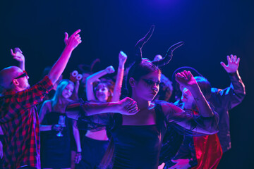 Fototapeta premium Halloween party scene with cheerful young boys and girls, students wearing various costumes, with creepy makeup, cheerful dancing at nightclub. Concept of Halloween, holiday, party, leisure