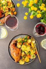 A hearty delicious dinner, baked rabbit with potatoes and carrots, a set table with food, a glass of wine and a vase of flowers