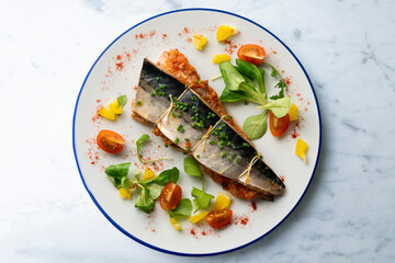 Baked mackerel stuffed with vegetables and tomato. Top view table.