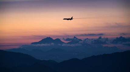 Jet soaring above mountains with evening clouds in the distance