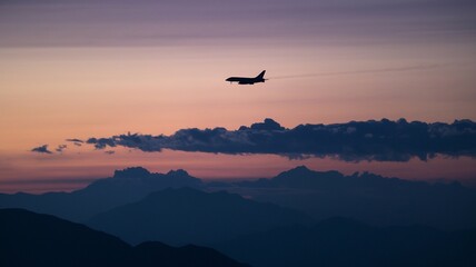 Fototapeta premium Jet soaring above mountains with evening clouds in the distance
