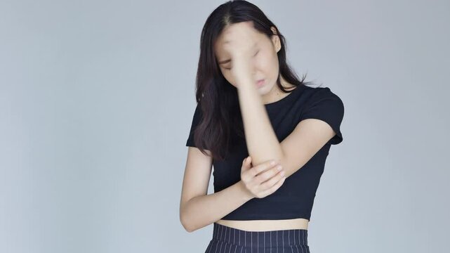 Asian woman suffering from tennis elbow syndrome or elbow joint pain, injury, rheumatoid or gout arthritis