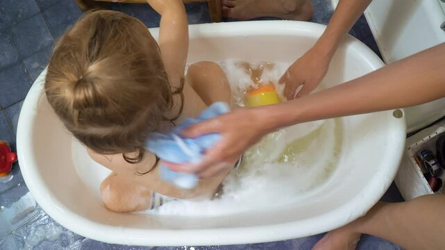 Adorable toddler boy taking a bath with mother. A mother bathing a baby in a bathtub.