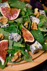 Whole and cut figs with blue cheese, nuts and arugula on a black background. Spicy taste. Mediterranean cuisine.