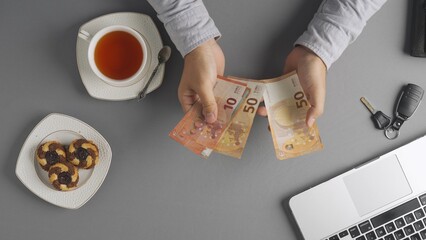 Top view of man at the table counting euro currency money banknotes and leaving it on the desk, paying bill at cafe or restaurant with cash.