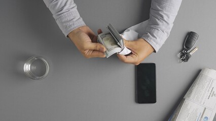 Top view of man counting wad of us dollars money banknotes in envelope and leaving it on the table, taking or borrowing money in credit.