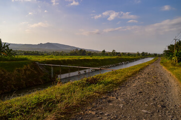 Fototapeta premium The view of the village in the morning. The expanse of rice fields, rivers and also mountains.