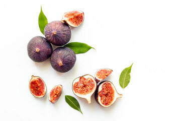 Whole and cut fresh figs with green leaves on white background. Top view