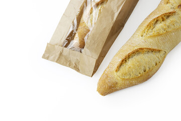 Two freshly baked baguettes, one wrapped in brown paper bag, Artisan French baguettes with crispy crusts in paper packaging. Isolated on a white background. Closeup. With clipping path.