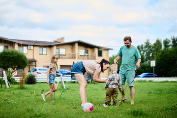 Obraz premium Happy family spending weekend in their backyard jumping rope and playing ball