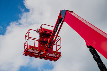 Red construction telescopic lift platform raised up in the air for lifting construction services of...