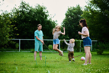 Happy family spending weekend in their backyard jumping rope and playing ball