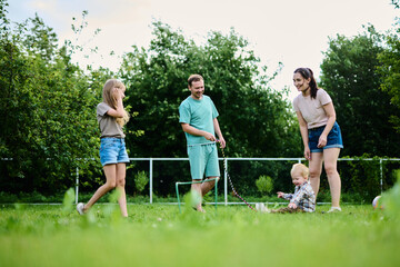 Happy family spending weekend in their backyard jumping rope and playing ball