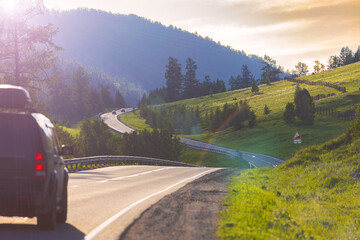 Sunny summer mountains landscape with winding asphalt road with cars driving in the Altai Republic,...