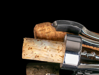 Several wine corks with metal opener, macro, isolated on black background.