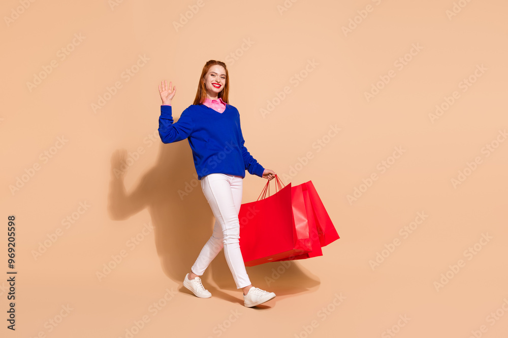 Wall mural Full size profile photo of nice young woman walk hold bags arm wave wear pullover isolated on beige color background