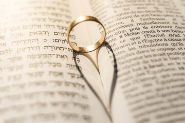 Fototapeta premium Gold ring on a Torah with a heart-shaped shadow