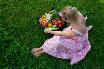 Modern housewife grows vegetables herself. Top view of blonde with fresh vegetables and tomato in hand.