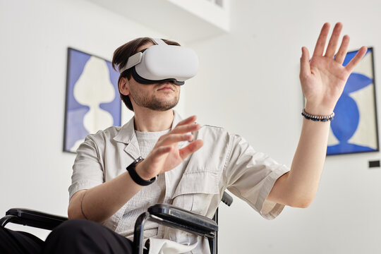 Portrait of man with disability using VR technology and interacting with invisible digital art piece in modern art museum setting