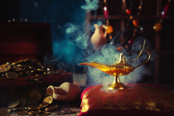 Precious golden magic lamp with smoke and wooden chest with coins.