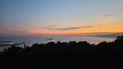 붉은 석양의 하늘과 바다, 산이 보이는 경관