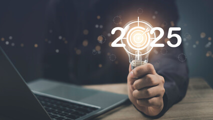 Hand hold light bulb target of 2024 to 2025. Start new year new Goals, Plans, and beginning startup...