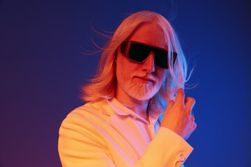 Stylish man with long hair in sunglasses against a colorful background, exhibiting confidence and...
