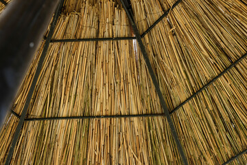 Beach umbrella made of natural materials. Beach umbrella knitted of reed. Umbrella Beach with a cane. View from below.