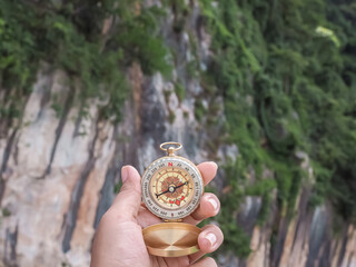 Close up of compass in woman hand with nature as background. The concept of world tourism day, Searching the right directions and Travel