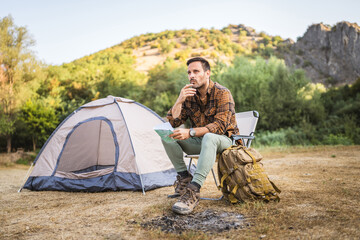 Adult man hiker sit on chair and read map look for the right way