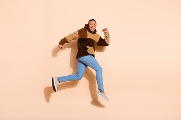 Photo of cheerful funny nice man wear stylish clothes run fast empty space isolated on beige color background