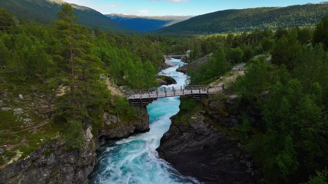 bridge over Tora River flowing along green hills landscape at Diktarstigen Hiking route in Sweden