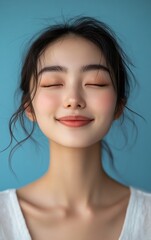 Close-up Portrait of Smiling Asian Woman in Natural Sunlight against Light Blue Background
