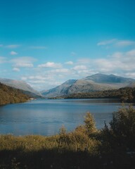 Naklejka premium Scenic vertical view of a tranquil lake surrounded by mountains in Brynrefail, Wales.