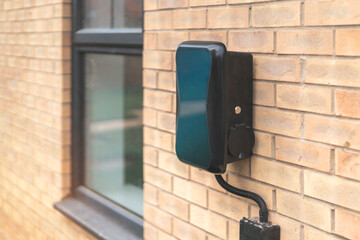 Stylish Electric Vehicle Charging Station Mounted on a Contemporary Brick Wall in an Urban Setting